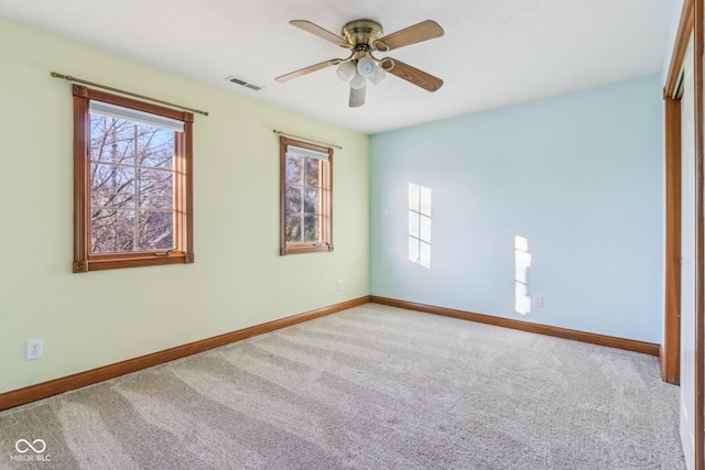 carpeted empty room featuring plenty of natural light, visible vents, and baseboards