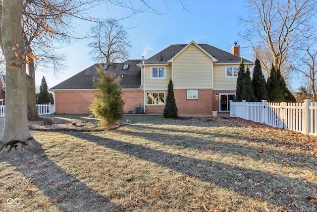 back of house with central air condition unit, fence, a lawn, and brick siding