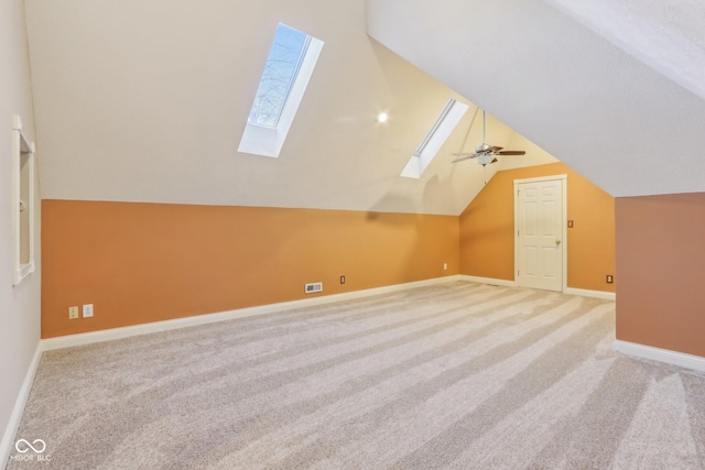 bonus room with carpet floors, lofted ceiling with skylight, visible vents, and baseboards