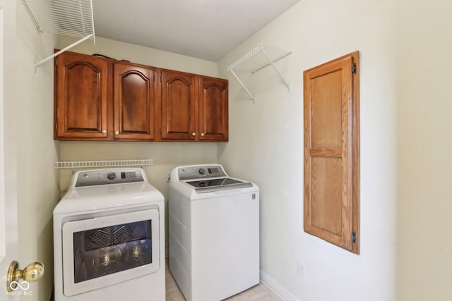 clothes washing area with washing machine and clothes dryer, cabinet space, and baseboards