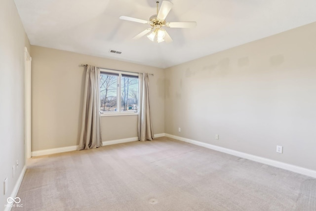 empty room with a ceiling fan, light colored carpet, visible vents, and baseboards