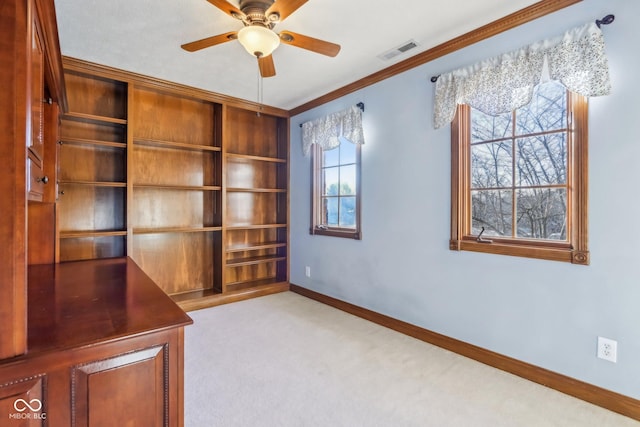 unfurnished office featuring carpet, visible vents, ornamental molding, a ceiling fan, and baseboards