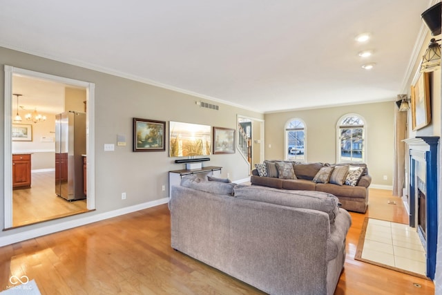 living area with a fireplace with flush hearth, visible vents, light wood-style flooring, and baseboards