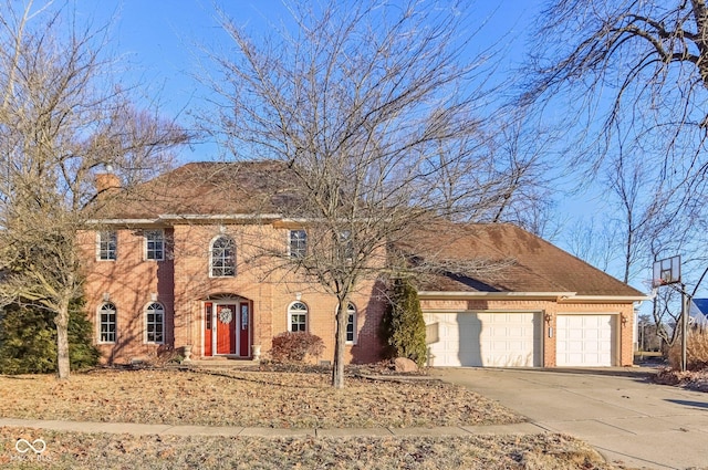 colonial home with brick siding, a chimney, a shingled roof, concrete driveway, and a garage