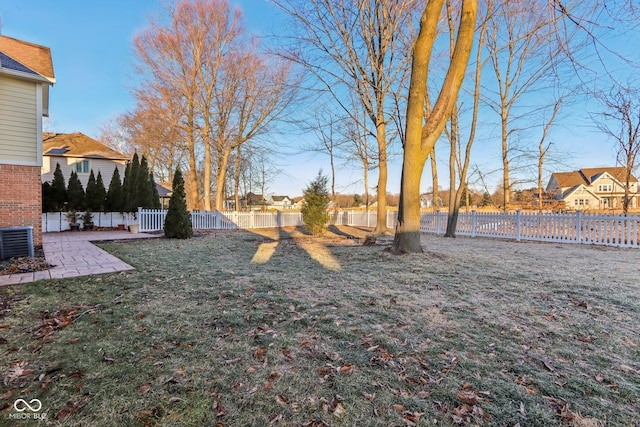 view of yard featuring central AC, a patio area, a fenced backyard, and a residential view