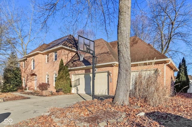 view of side of home with a shingled roof, concrete driveway, brick siding, and an attached garage