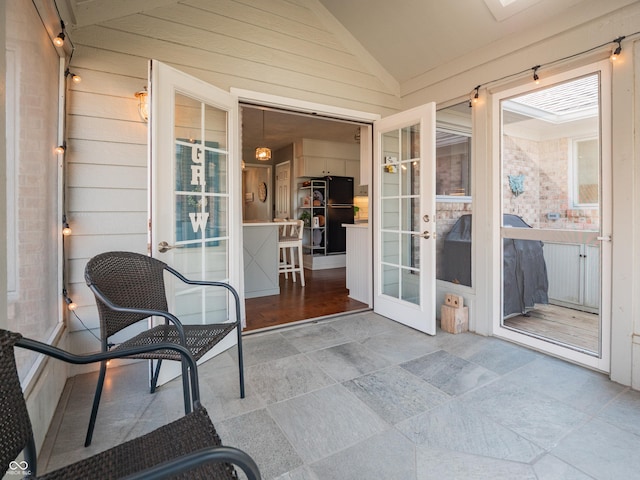 sunroom featuring vaulted ceiling and french doors