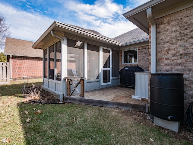 exterior space with roof with shingles, brick siding, a yard, fence, and a wooden deck