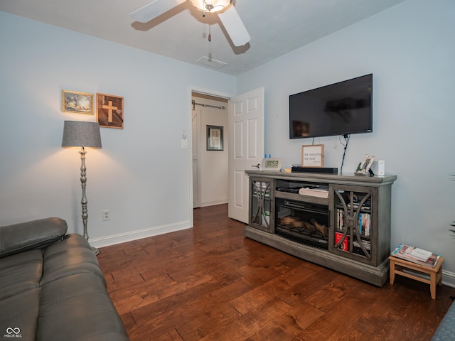 living room with dark wood-style flooring, visible vents, ceiling fan, and baseboards