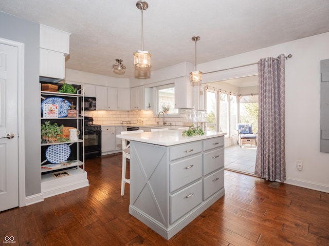 kitchen with dark wood finished floors, light countertops, a sink, and black appliances