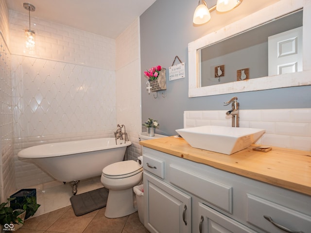 bathroom with a freestanding tub, vanity, tile walls, and tile patterned floors