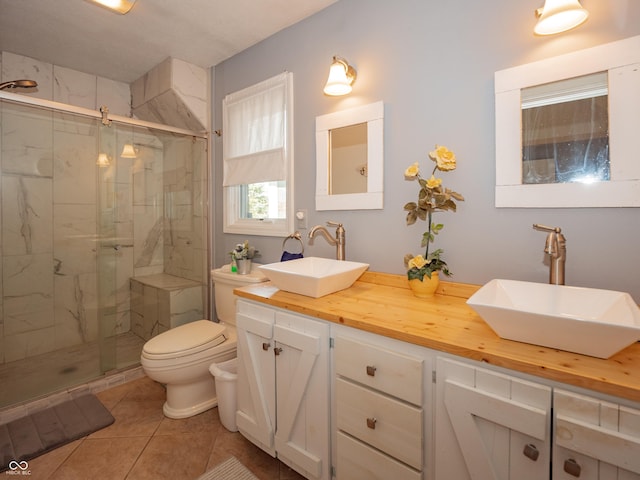 full bathroom with a stall shower, a sink, toilet, and double vanity