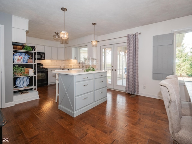 kitchen featuring dark wood-style flooring, light countertops, black appliances, and white cabinets