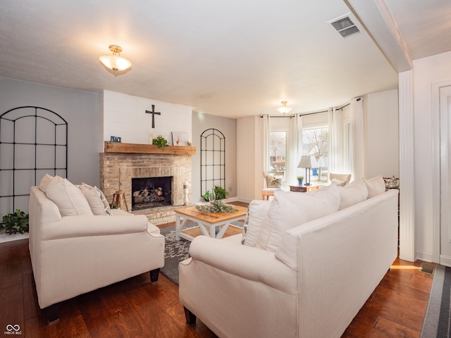 living area featuring dark wood-style floors, visible vents, and a fireplace