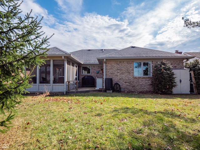 back of property featuring brick siding, a shingled roof, a sunroom, a lawn, and a patio area