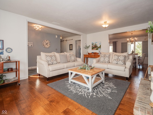 living area with baseboards, hardwood / wood-style flooring, and a notable chandelier