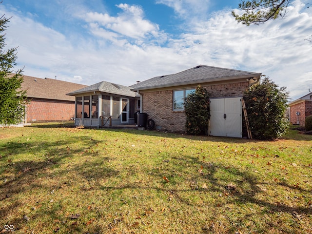 back of house with a sunroom, brick siding, and a yard