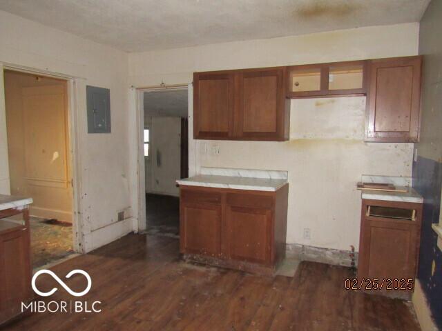 kitchen featuring dark wood-style floors, electric panel, brown cabinets, and light countertops