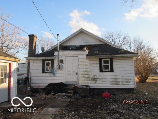 back of property with entry steps and a chimney