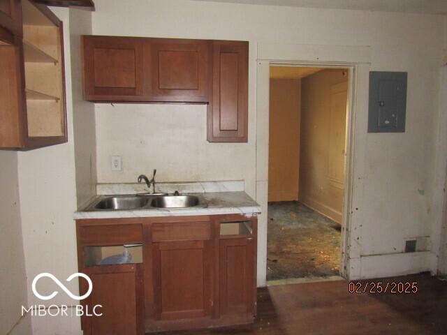 kitchen with light countertops, a sink, electric panel, and brown cabinets