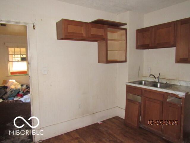 kitchen with brown cabinets, dark wood-type flooring, a sink, and light countertops