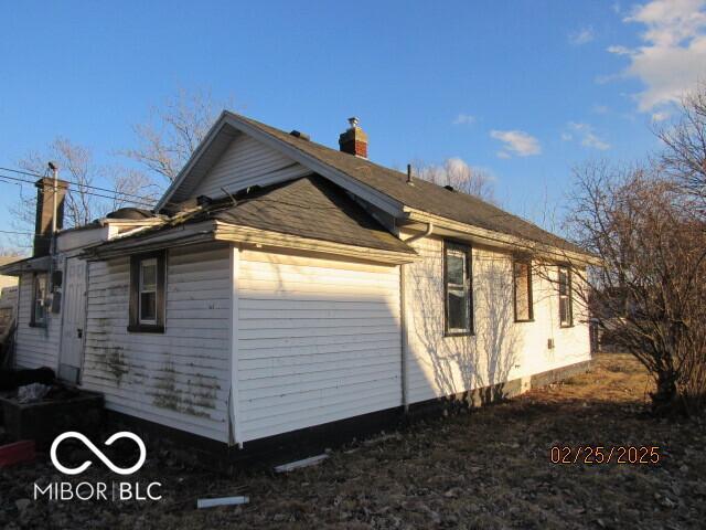 view of side of property featuring a chimney and an attached garage