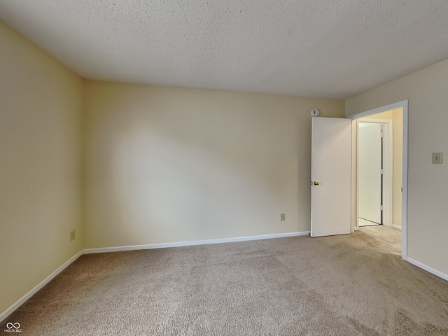 spare room with carpet floors, a textured ceiling, and baseboards