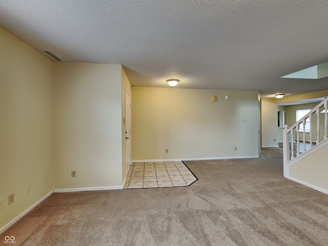 unfurnished room featuring baseboards, visible vents, stairway, a textured ceiling, and carpet floors