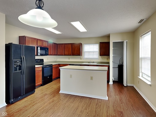 kitchen with light wood-type flooring, light countertops, visible vents, and black appliances