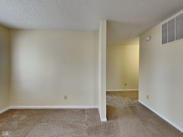 unfurnished room featuring carpet floors, baseboards, visible vents, and a textured ceiling