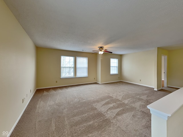 unfurnished room with carpet floors, a textured ceiling, baseboards, and a ceiling fan