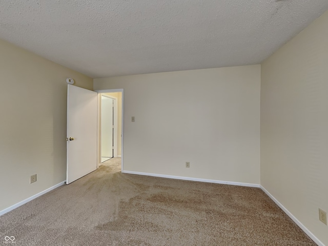 spare room featuring carpet flooring, a textured ceiling, and baseboards