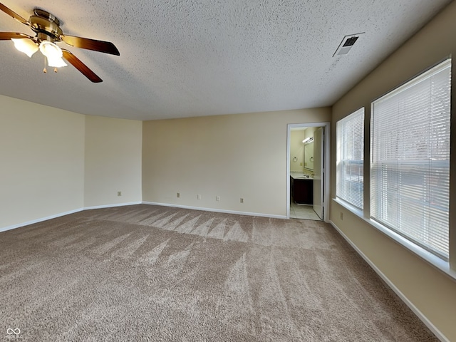 empty room with baseboards, a textured ceiling, visible vents, and light colored carpet