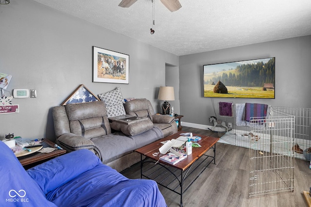 living room with a textured ceiling, ceiling fan, wood finished floors, and baseboards