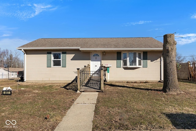 view of front of property with a shingled roof, fence, and a front yard