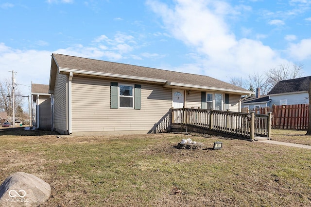 ranch-style home with a front yard, fence, and a wooden deck