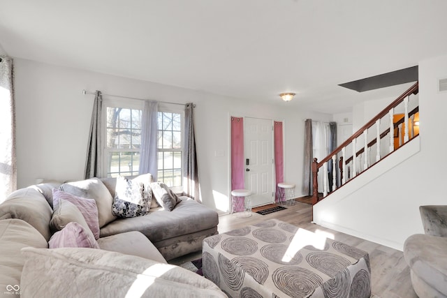 living area with stairway, light wood-style floors, and visible vents