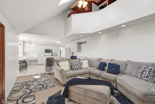 living room featuring visible vents, light colored carpet, ceiling fan with notable chandelier, a skylight, and high vaulted ceiling