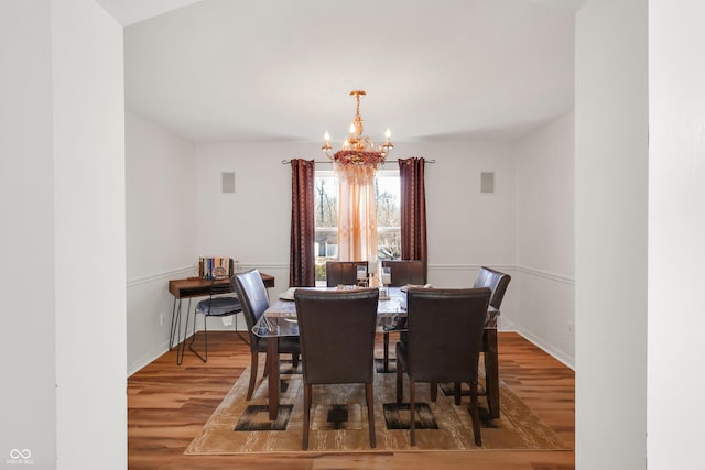 dining space featuring a notable chandelier, baseboards, and wood finished floors