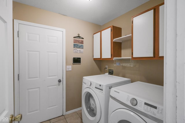 clothes washing area featuring light tile patterned floors, cabinet space, and washing machine and clothes dryer