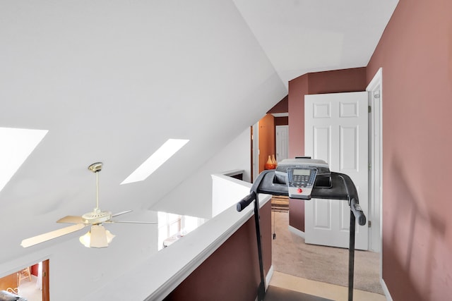 interior space with light carpet, ceiling fan, and vaulted ceiling with skylight