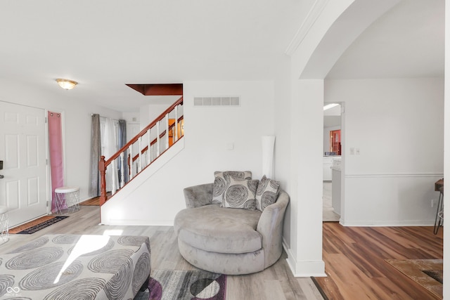 entrance foyer with visible vents, wood finished floors, arched walkways, baseboards, and stairs