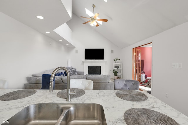 kitchen featuring a sink, light stone counters, recessed lighting, a fireplace, and ceiling fan