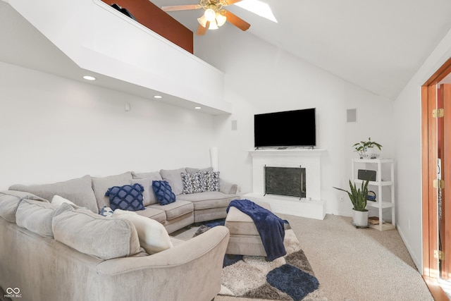 carpeted living room featuring visible vents, a fireplace, a skylight, high vaulted ceiling, and a ceiling fan