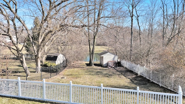 view of yard with an outbuilding, a storage unit, fence, and a water view