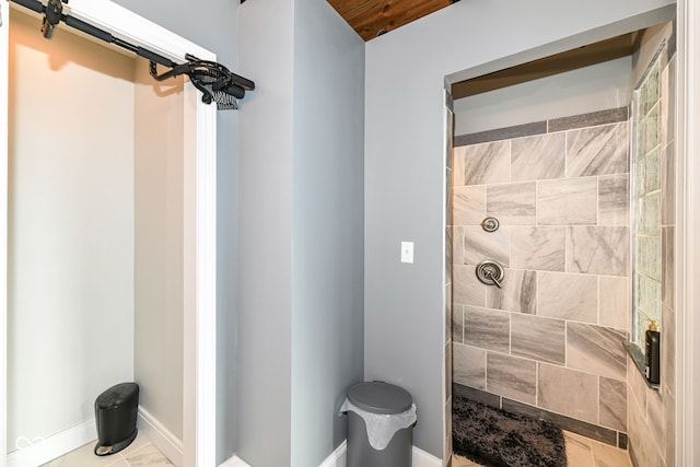 bathroom with tiled shower and baseboards