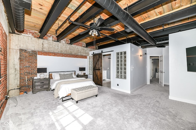 unfurnished bedroom with a walk in closet, a barn door, carpet flooring, brick wall, and baseboards