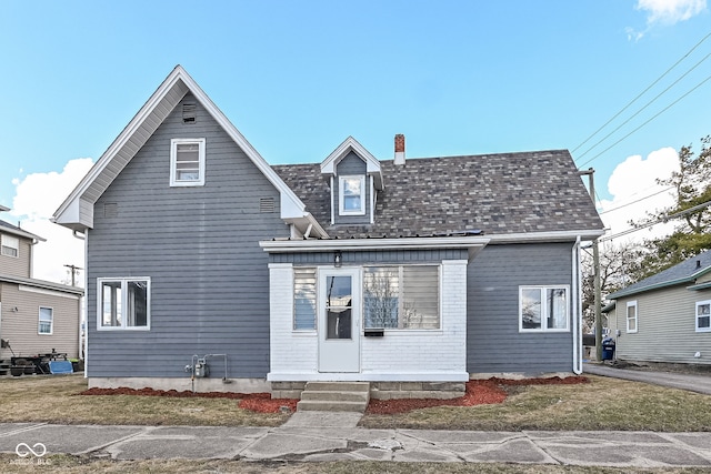 view of front of house with entry steps, roof with shingles, and a chimney