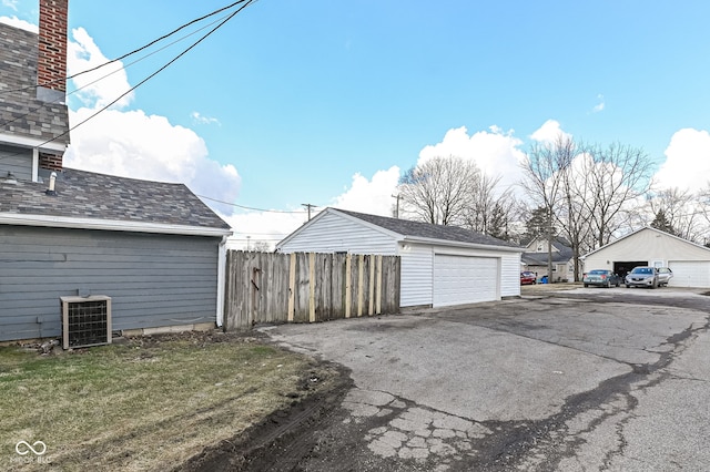 detached garage featuring fence and central air condition unit