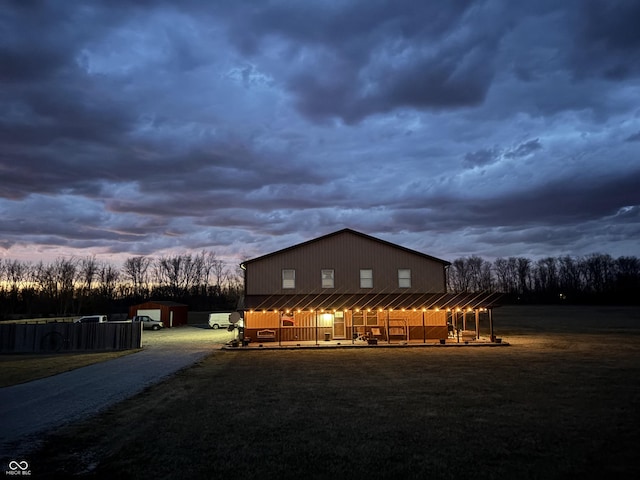 property exterior at dusk featuring an outbuilding, driveway, and a lawn